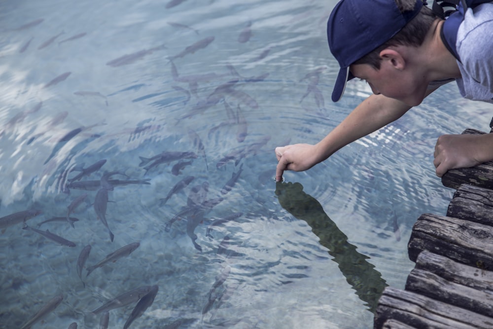 boy in blue cap and blue tank top in water