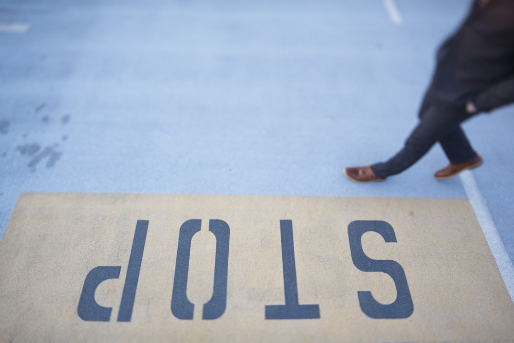 person waling on gray pavement with stop print