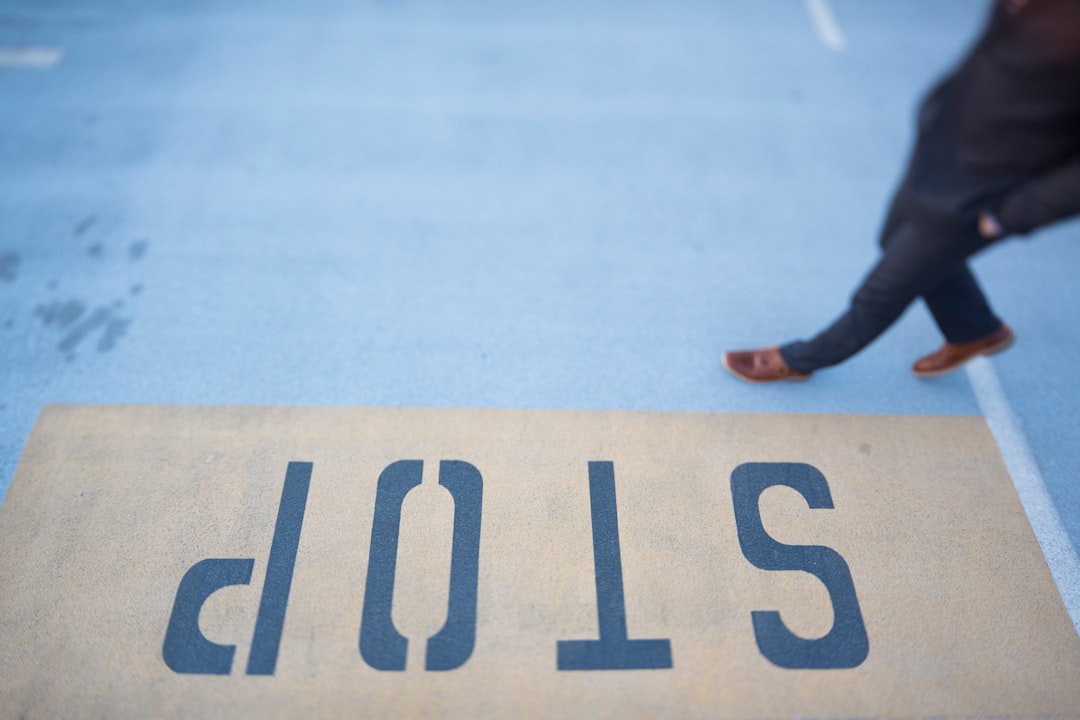 person waling on gray pavement with stop print