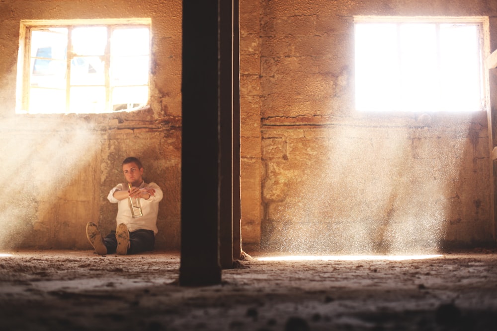 man sitting beside concrete wall