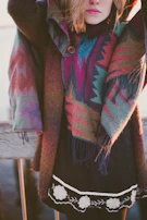 A model wearing a modern poncho with Andean patterns against a rustic village backdrop.