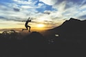 person jumping on hill during sunset