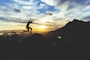person jumping on hill during sunset