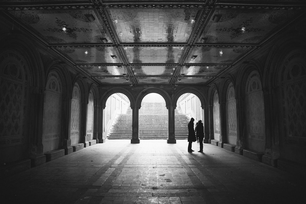grayscale two people standing on hallway