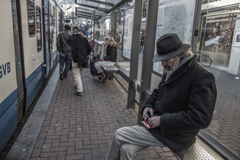 man sitting on waiting bench in train station