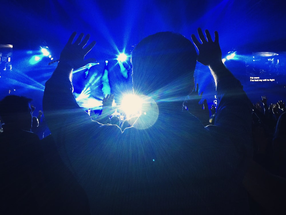 silhouette of a person raising hands towards the stage