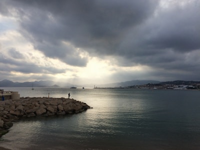 A scenic view of a UK coastline with a fisherman casting his line.