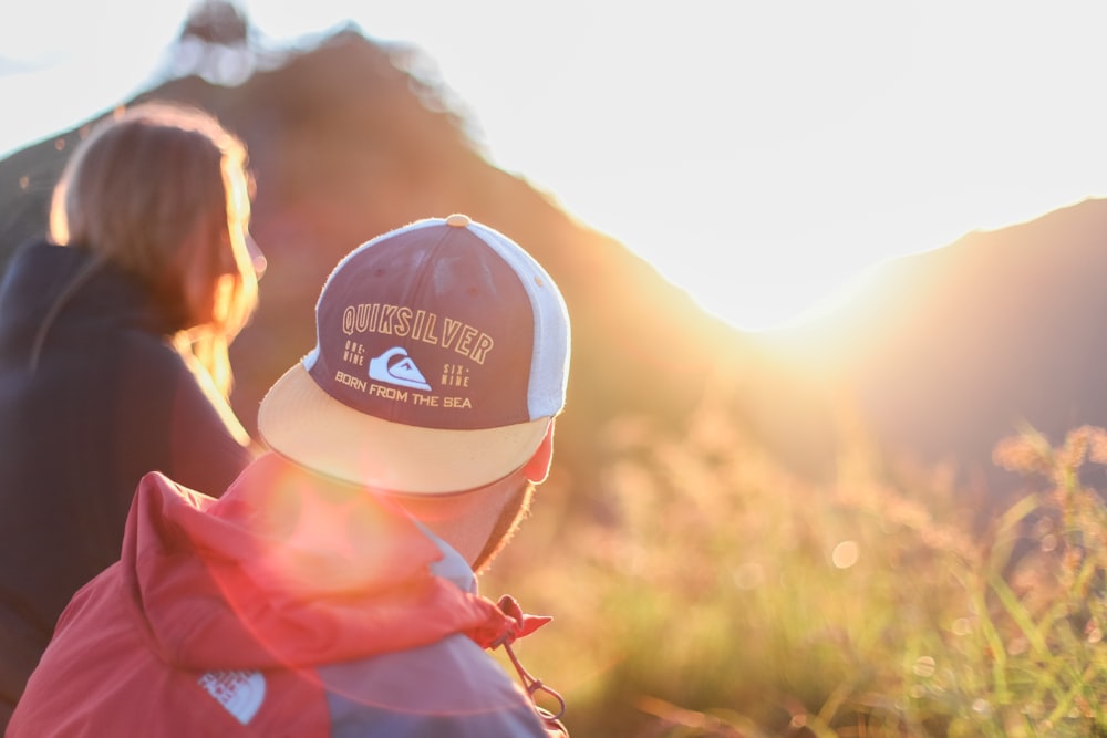 shallow photography of of man and woman sitting looking at sun rise