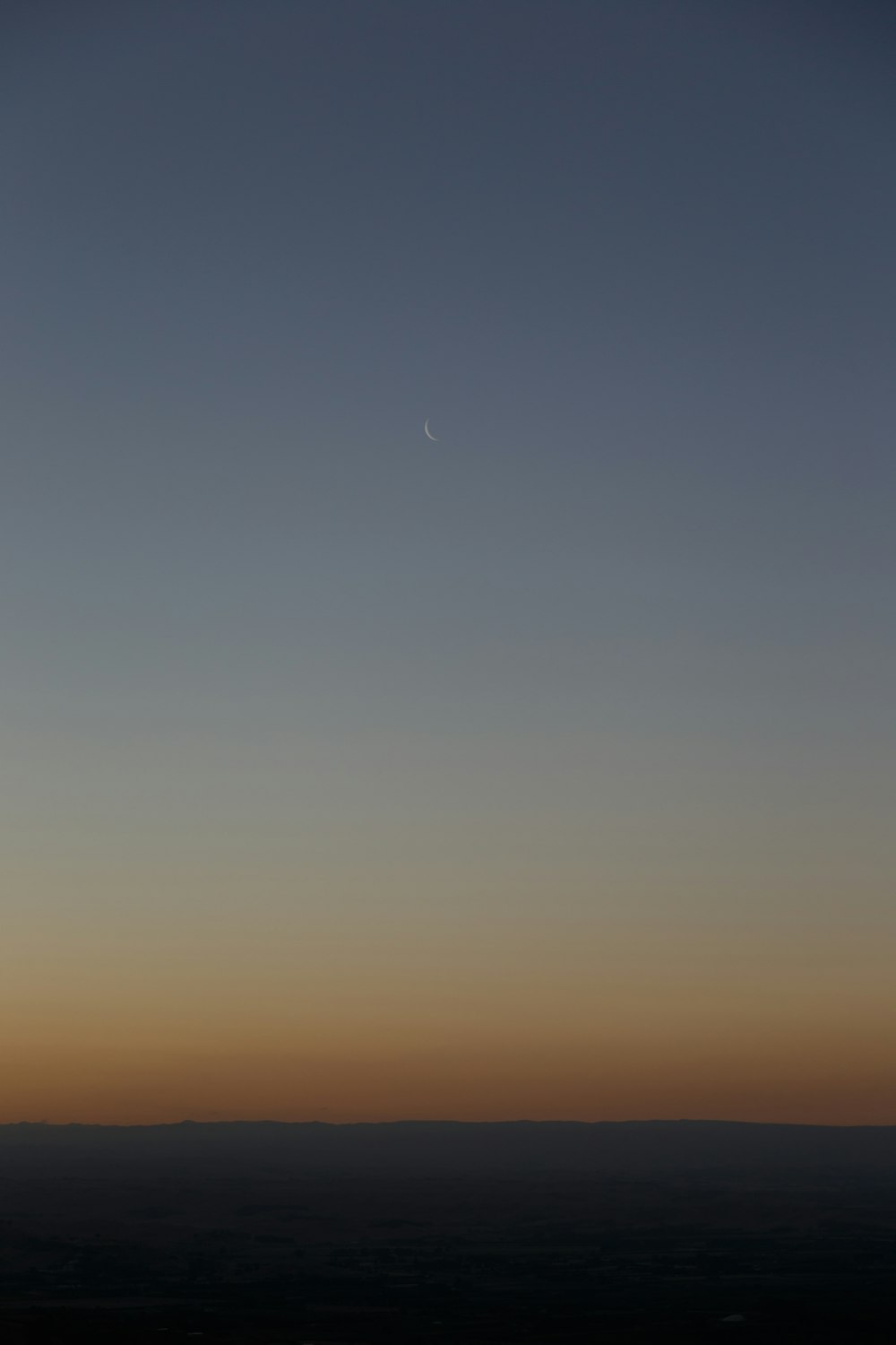 brown and blue horizon with crescent moon