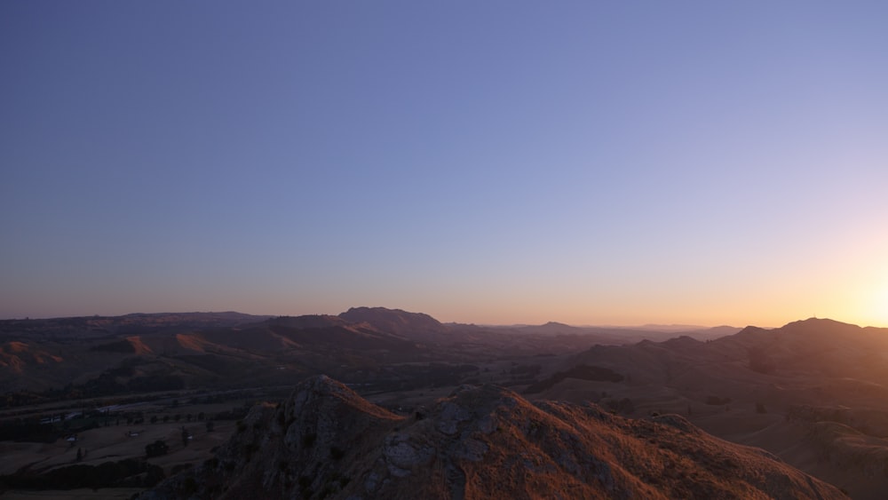 brown hills under blue sky during sunrise