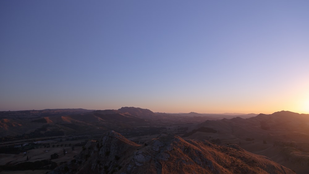 日の出の青空の下の茶色の丘