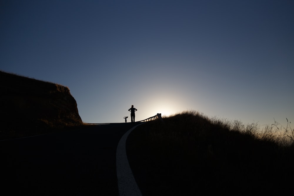 silhouette photo of person above hill