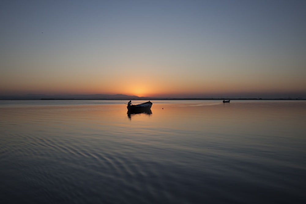 silhouette of boat on body of water during golden hour