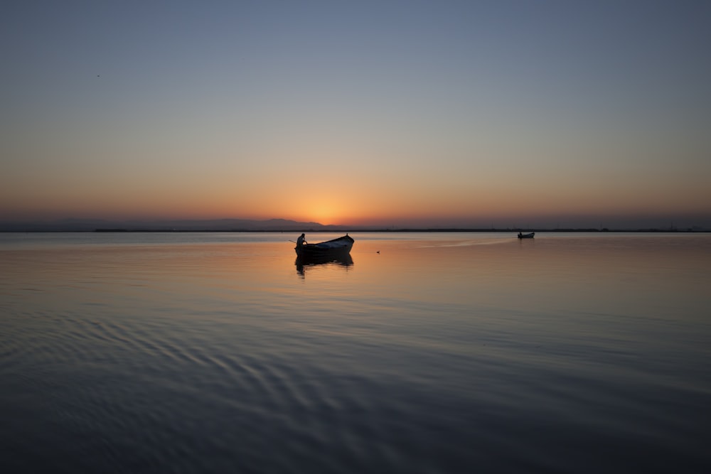 Silhouette eines Bootes auf einem Gewässer während der goldenen Stunde