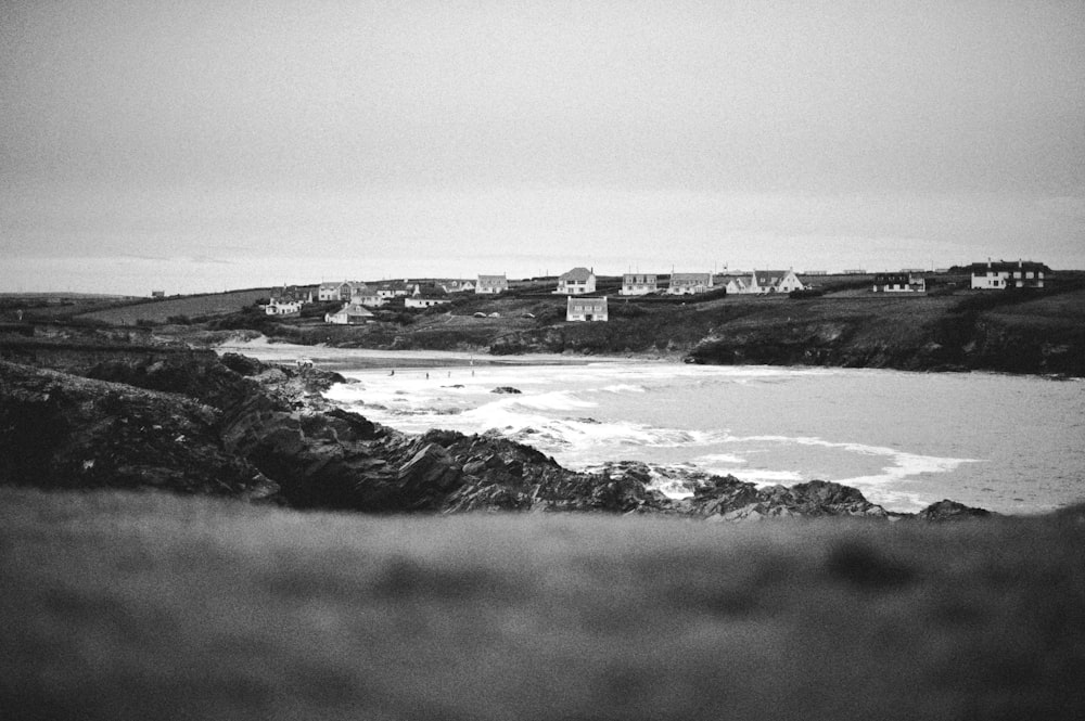 Photographie en niveaux de gris de maisons au bord d’une rivière