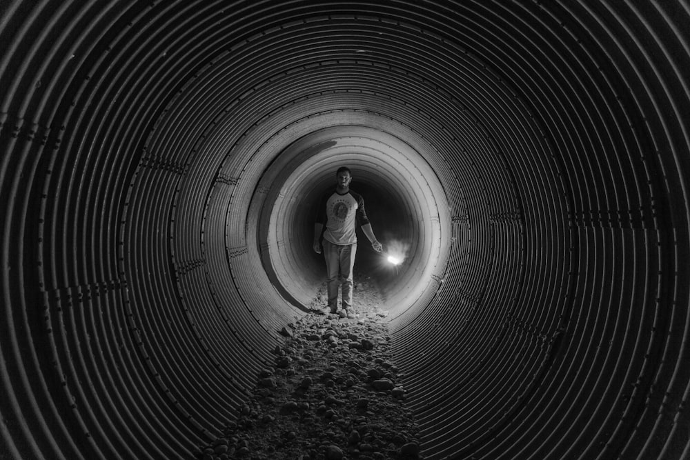 grayscale photography of person walking on tunnel