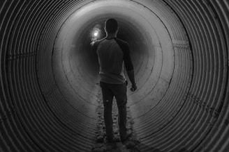 man holding light walking inside tunnel