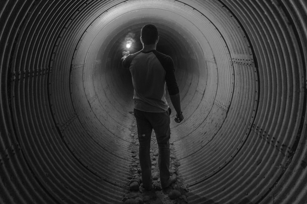 man holding light walking inside tunnel