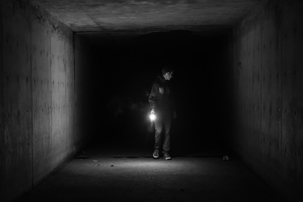 grayscale photography of person walking on tunnel