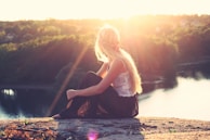 woman sitting on brown surface watching at body of water