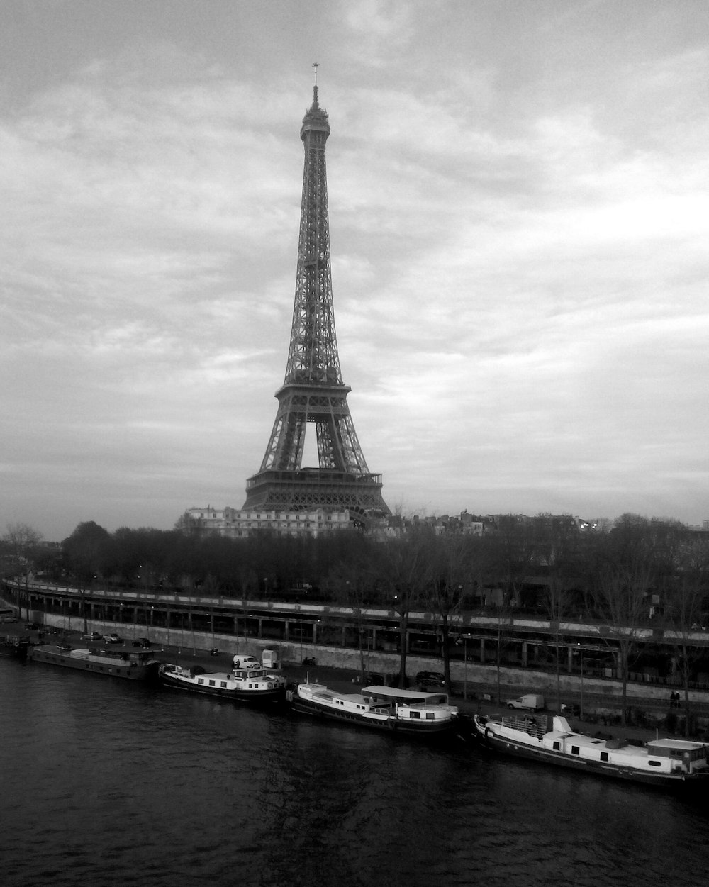 에펠탑과 부두 근처에 정박한 보트의 회색조 사진