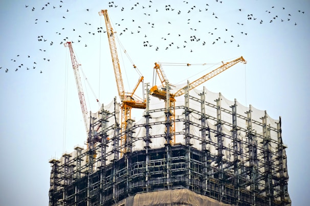 High-resolution drone shot capturing a construction site mid-progress with cranes and workers.