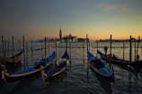 Colorful gondolas gently floating along a narrow Venetian canal at dusk.