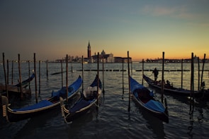 Colorful gondolas gently floating along a narrow Venetian canal at dusk.
