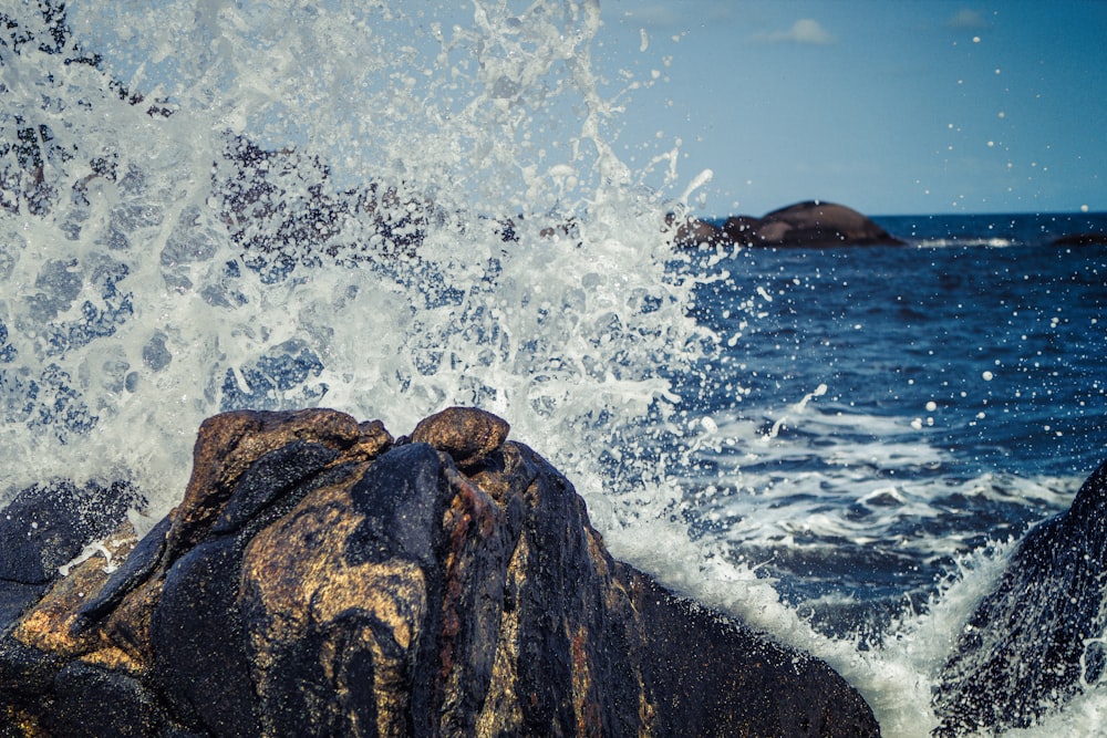 seawater splashing rock boulders at daytime