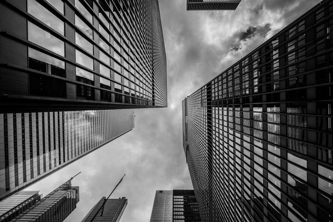 A black-and-white shot of white clouds above towering high-rises in a city