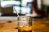 Iced coffee in a glass jar with condensation, surrounded by soft terracotta and cream-colored linens.