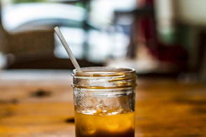 Iced coffee in a glass jar with condensation, surrounded by soft terracotta and cream-colored linens.