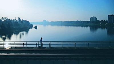 person walking on bridge near body of water