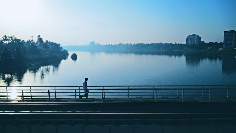 person walking on bridge near body of water