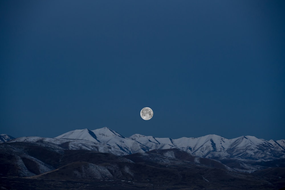 luna llena sobre pintura de montaña cubierta de nieve