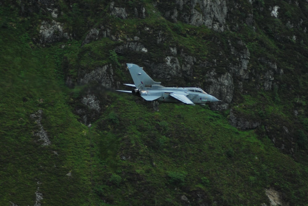 gray fighter jet near the mountain