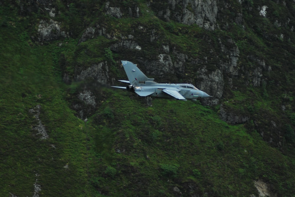 Grauer Kampfjet in der Nähe des Berges