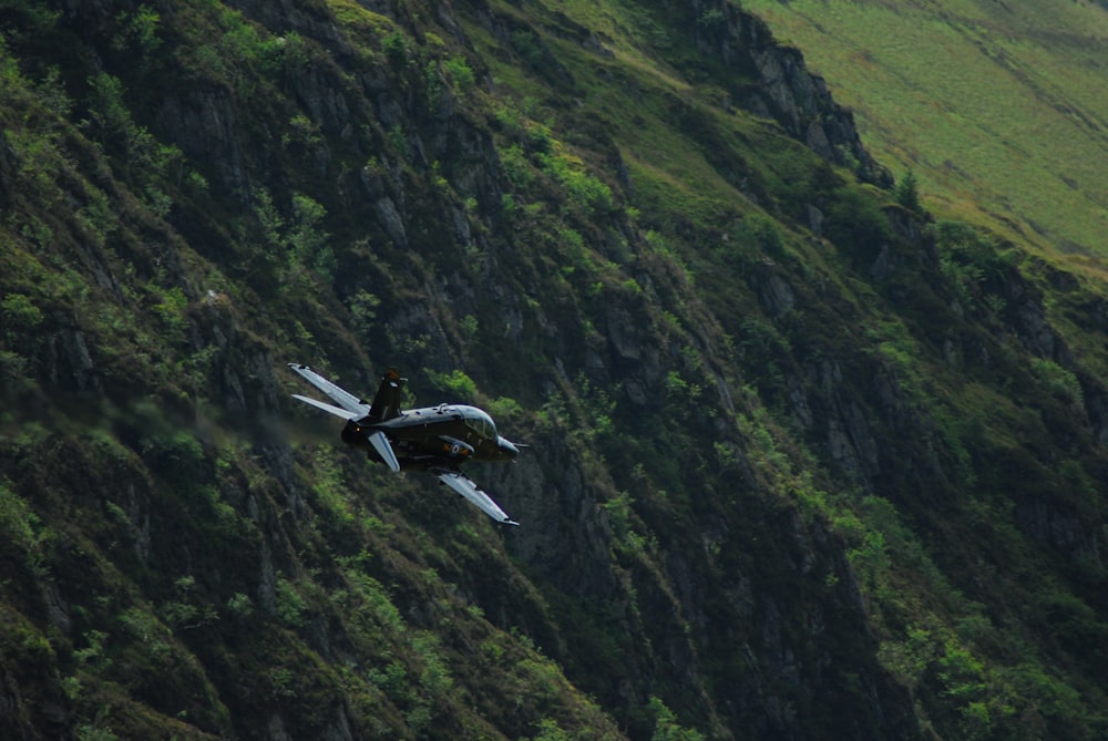 Schwarzes Verkehrsflugzeug im Flug über grünen Bergen