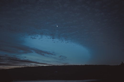 A serene night sky filled with stars and a glowing crescent moon over a tranquil landscape.