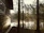 Morning view of a wooden cabin with mist over the lake and tall pine trees in the background.