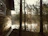 Morning view of a wooden cabin with mist over the lake and tall pine trees in the background.
