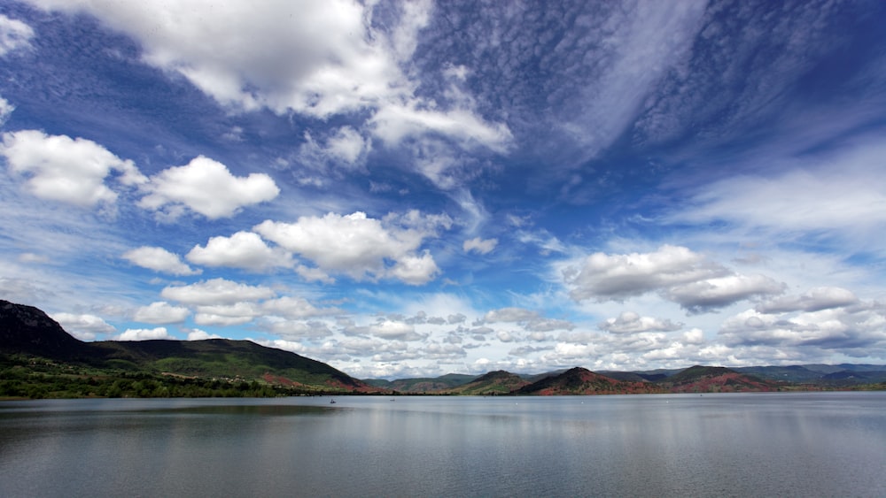 body of water near mountain during daytime