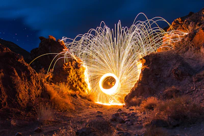 Nighttime blasting with bright sparks illuminating the rocky terrain.
