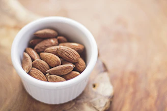 A rustic bowl filled with crunchy, roasted almonds on a wooden table.