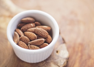 shallow focus photography of almonds in white ceramic bowl