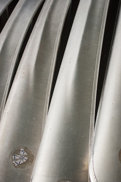 Close-up of coated flat-rolled steel sheets reflecting light in a factory setting.