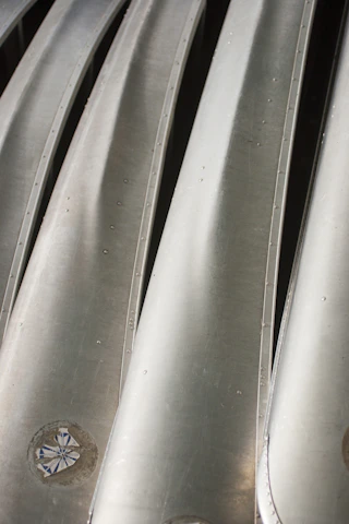 A close-up of shiny metal sheets stacked neatly in a warehouse, reflecting light.