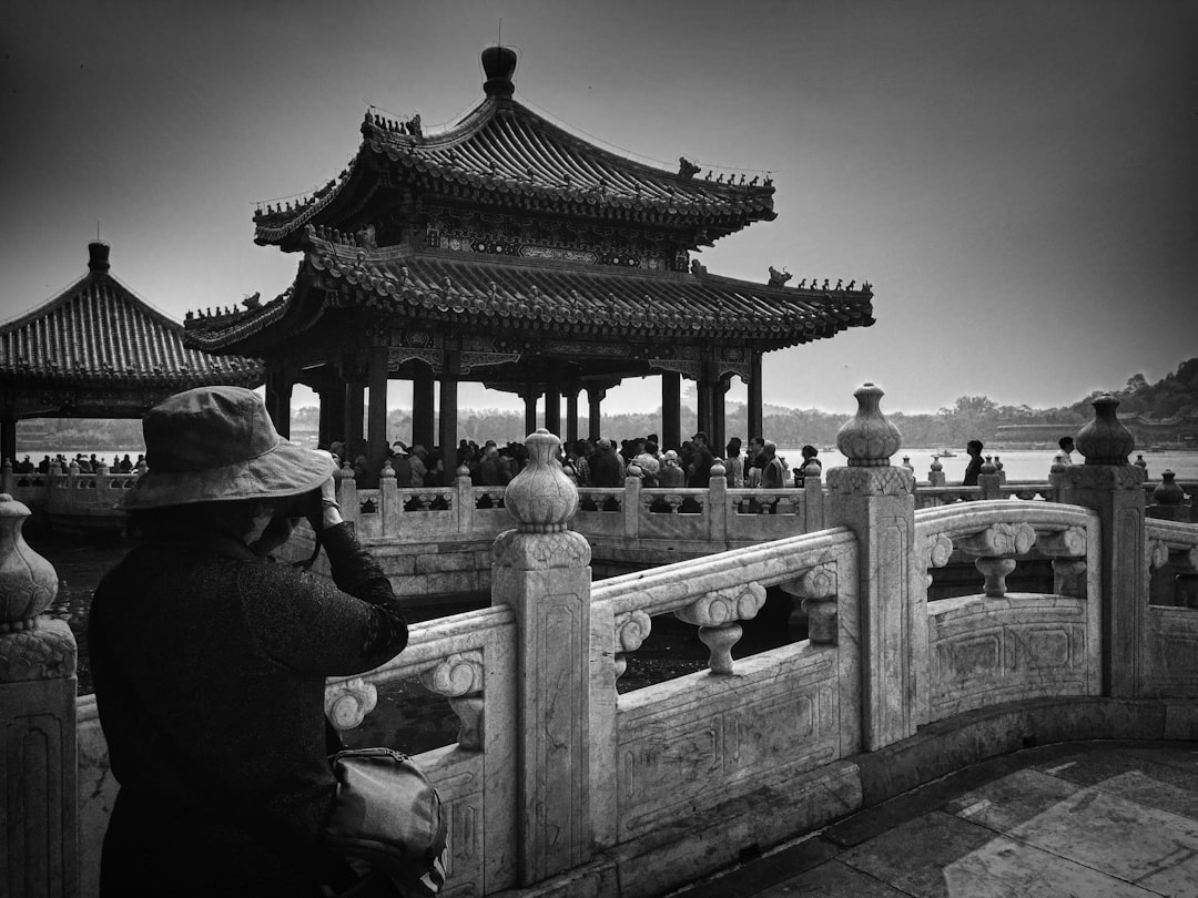 grayscale photo of woman taking photo of temple with people