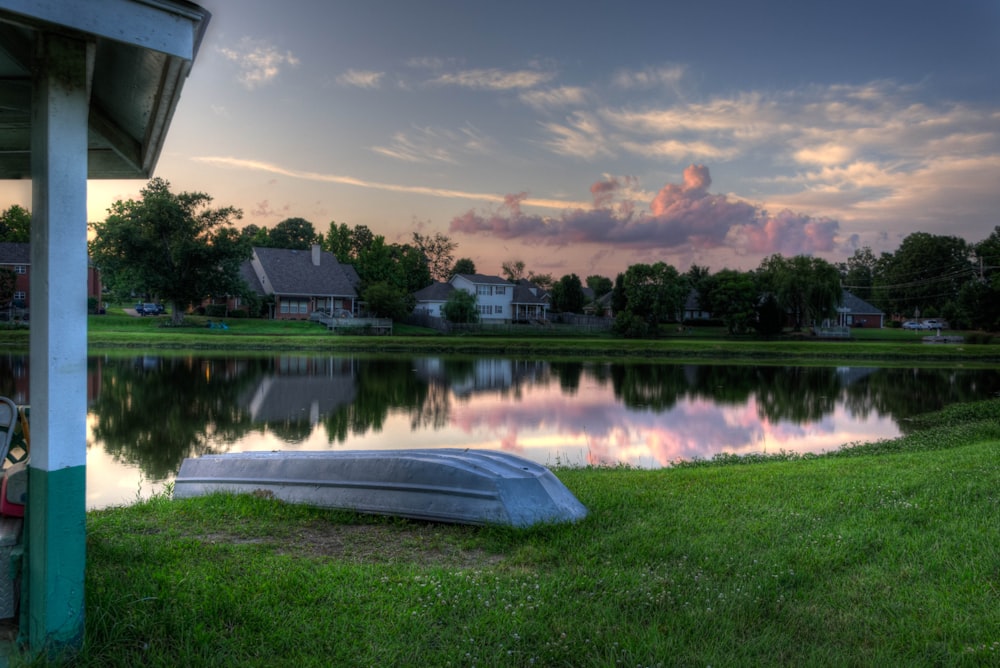 white wooden boat on green grass field beside body of water