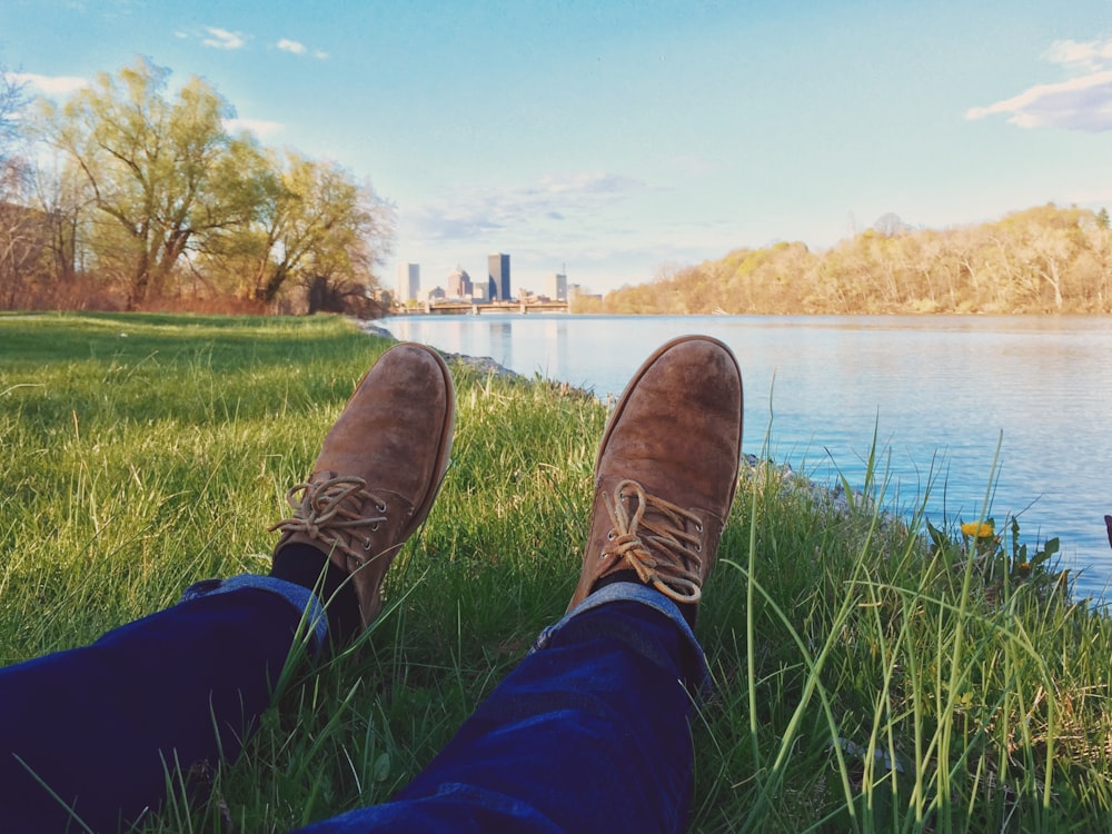 person lying on grass front of body ofwater